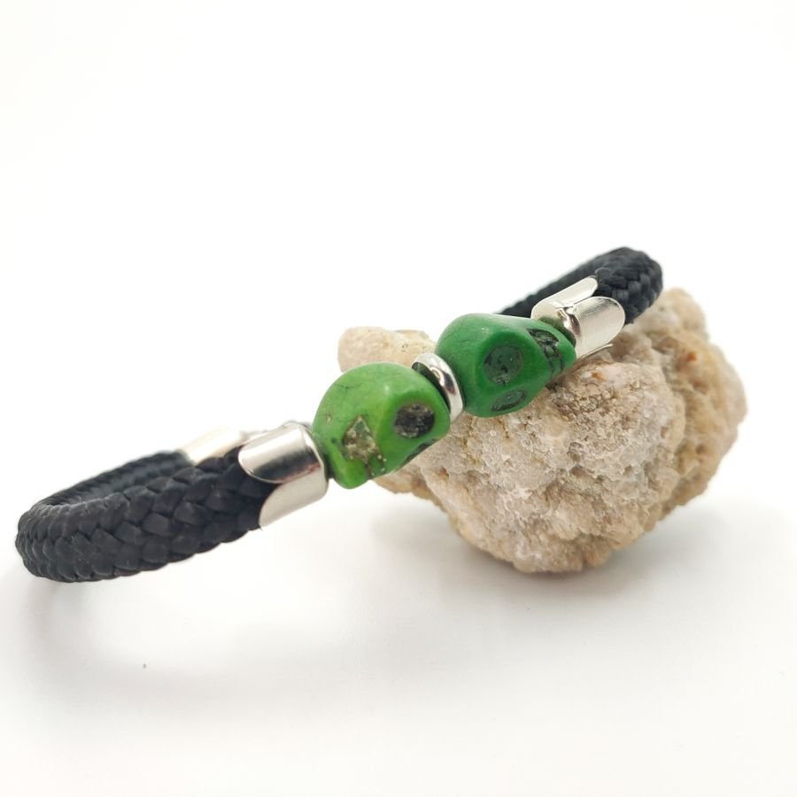 Double skull and crossbones bracelet with green stones on black rope